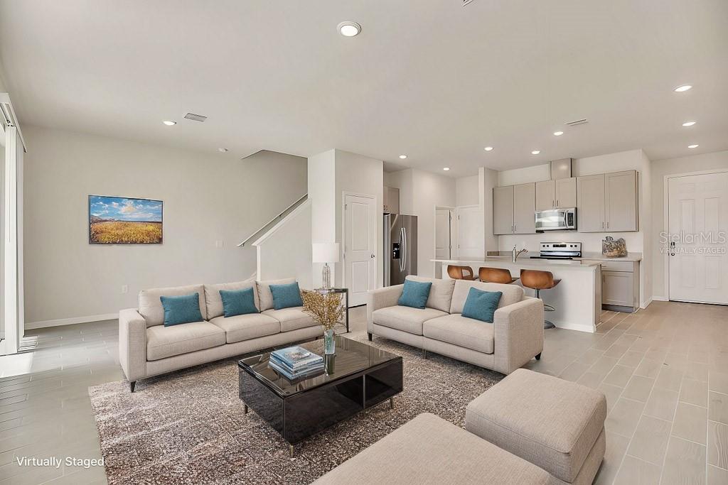 A living room with light tile floors, two sofas, a coffee table, and an open kitchen — 1758 WOODLEAF HAMMOCK COURT, BRADENTON, FL