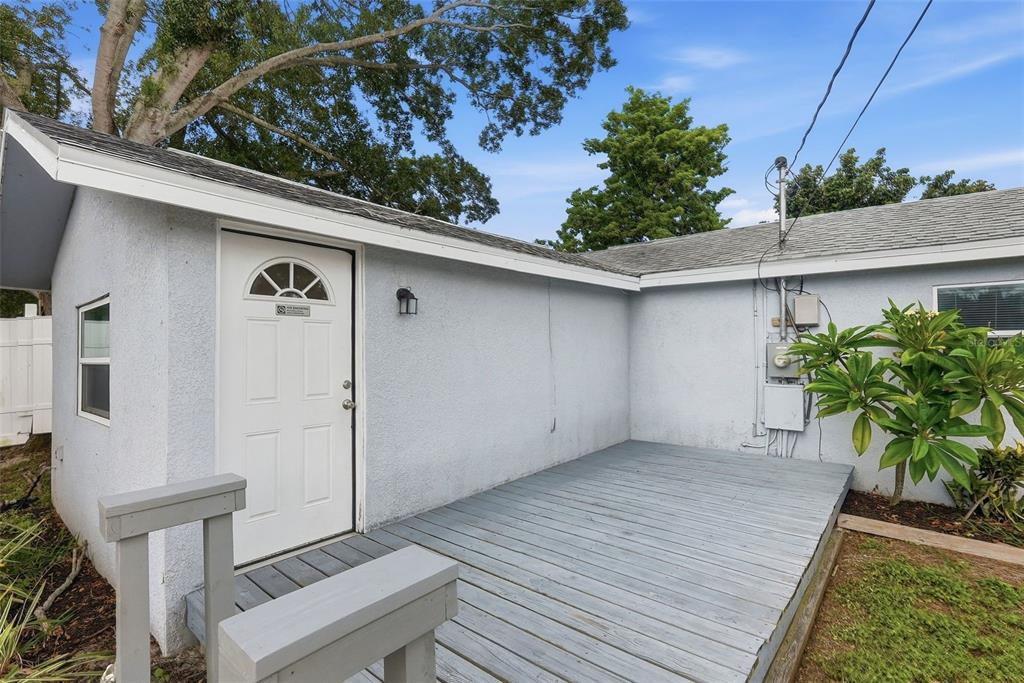 A light blue exterior wall features a white door leading to a gray wooden deck — 4978 71ST STREET N, ST PETERSBURG, FL