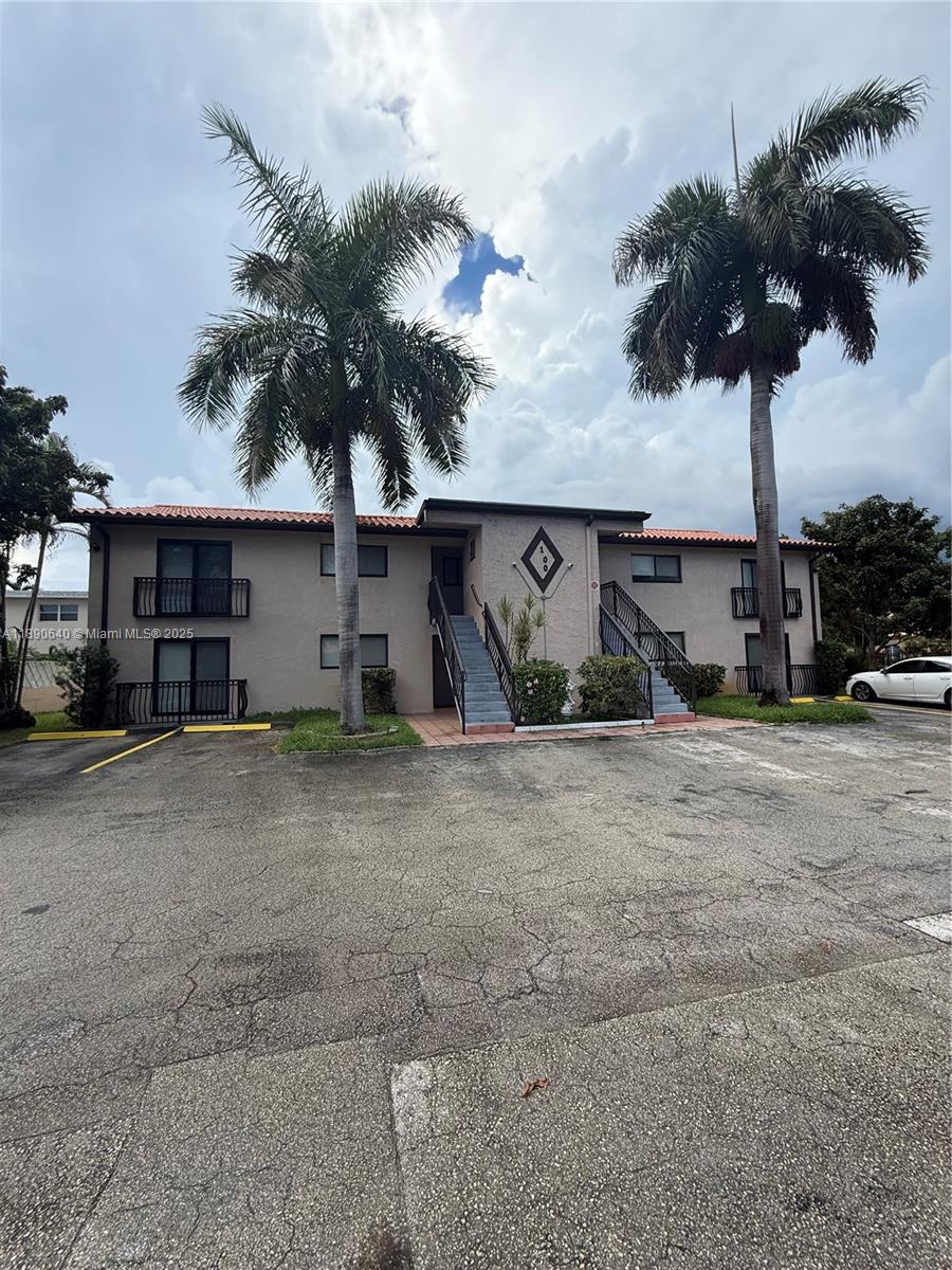 A two-story apartment building with a stucco exterior, two staircases, and two tall palm trees — 100 SE 5th Ave # 1, Hallandale Beach FL 33009, HALLANDALE BEACH, FL