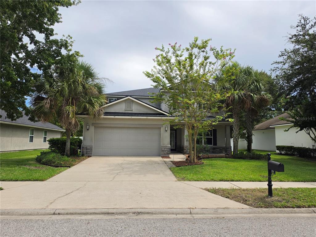 A two-story suburban house with a two-car garage, palm trees, and a front lawn — 404 PAISLEY PLACE, ST JOHNS, FL
