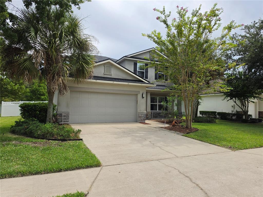 A two-story house with a beige stucco exterior, a two-car garage, and a concrete driveway — 404 PAISLEY PLACE, ST JOHNS, FL
