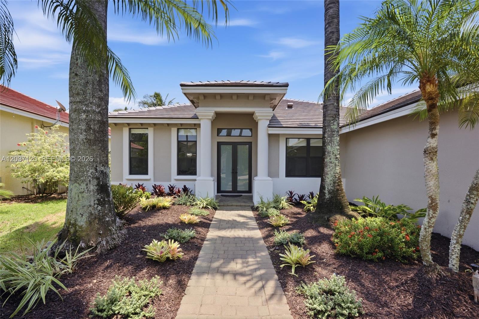 The exterior of a single-story house features a paved walkway leading to a double-door entrance — 2048 Quail Roost Dr, Weston FL 33327, WESTON, FL