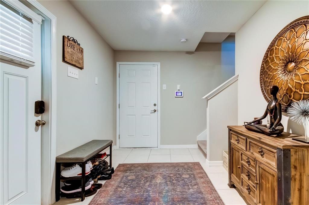 An entryway features a shoe bench, a wooden cabinet, a rug, and a white door — 4626 WILLET COOPER COURT, TAMPA, FL
