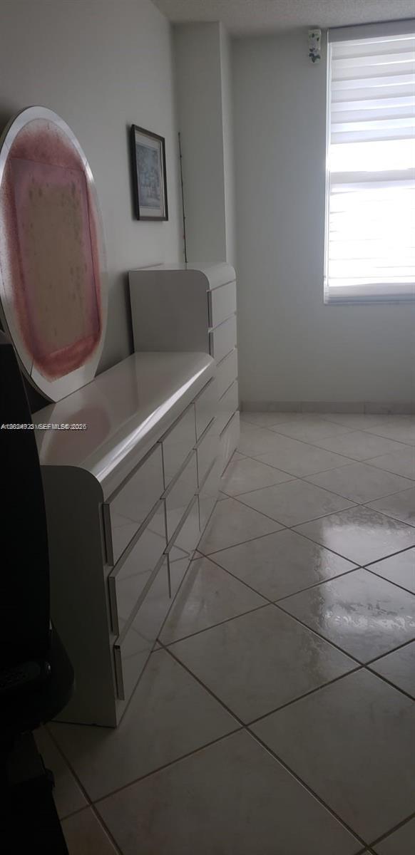A bedroom features white tile floors, a white dresser, and a large circular mirror — 3725 S Ocean Dr # 1208, Hollywood FL 33019, HOLLYWOOD, FL