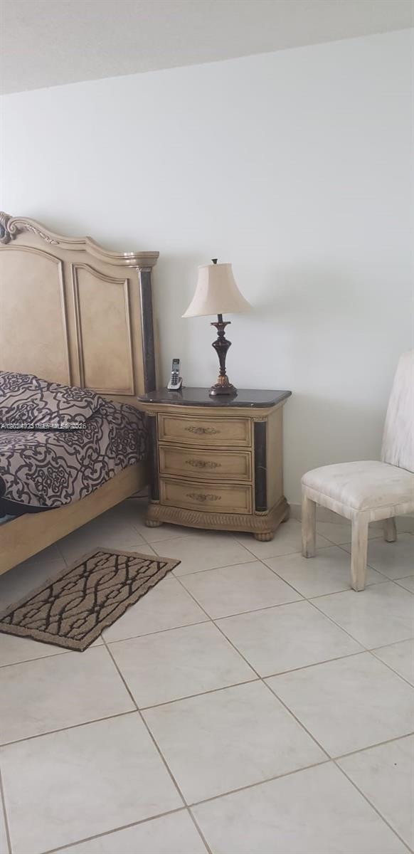 A bedroom features a wooden headboard, a three-drawer nightstand with a lamp, and a chair — 3725 S Ocean Dr # 1208, Hollywood FL 33019, HOLLYWOOD, FL