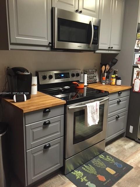 A kitchen features gray cabinets, stainless steel appliances, and a butcher block countertop — 9134 SW 118th Ct, Miami FL 33186, MIAMI, FL