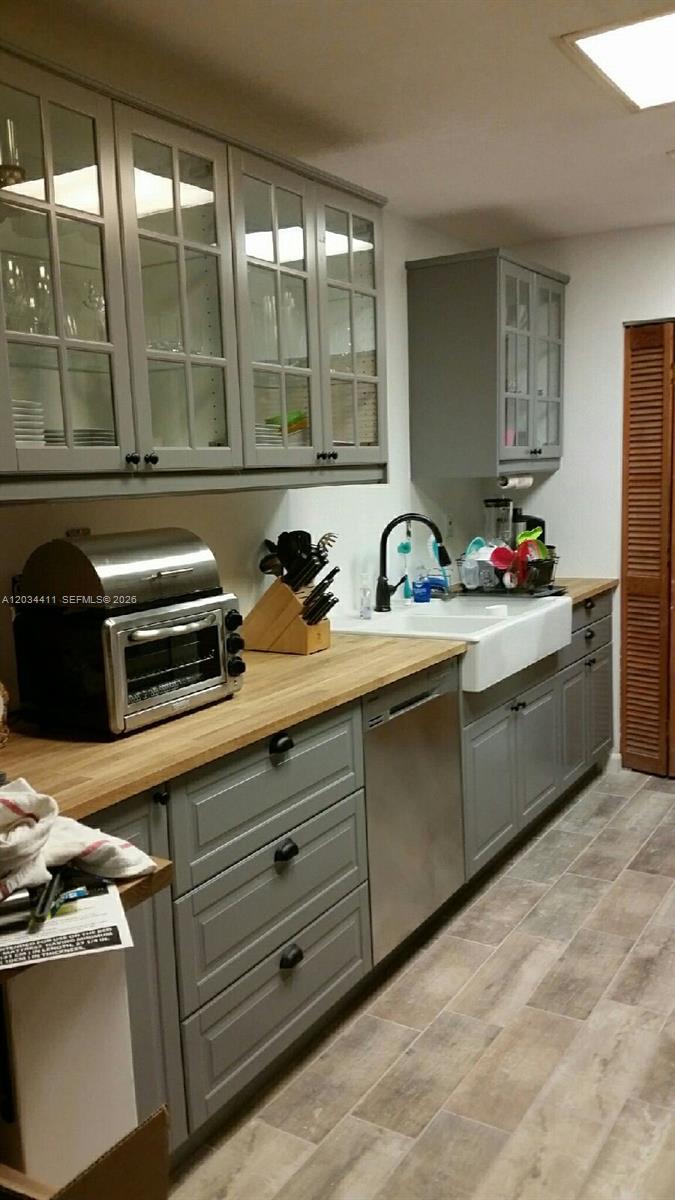 A kitchen features gray cabinets, a wood countertop, a farmhouse sink, and stainless steel appliances — 9134 SW 118th Ct, Miami FL 33186, MIAMI, FL