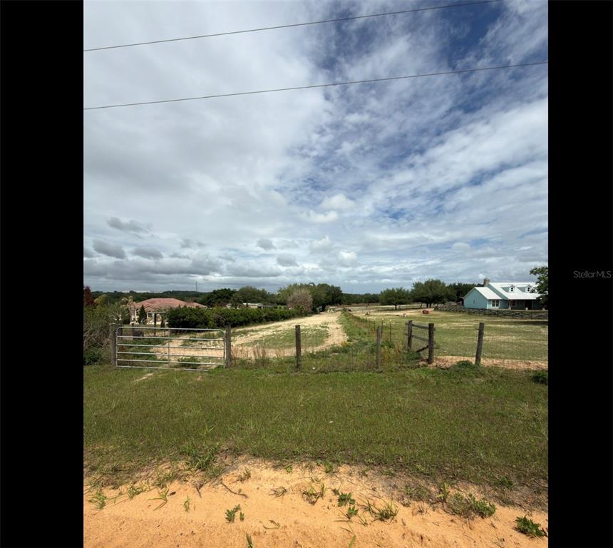 A fenced, grassy lot with a dirt driveway leads toward a house in the distance — LIBBY NO 3 ROAD, GROVELAND, FL