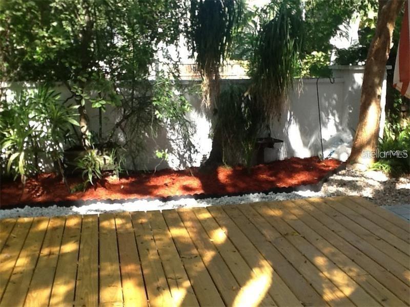 A wooden deck sits in front of a garden bed with red mulch and a white wall — 5300 BAYSHORE BOULEVARD UNIT A5, TAMPA, FL