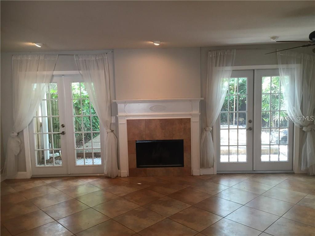 A living room features a tiled fireplace, light-colored tile floors, and two sets of French doors — 5300 BAYSHORE BOULEVARD UNIT A5, TAMPA, FL
