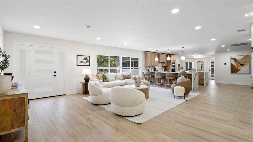 An open-concept living room and kitchen featuring light wood flooring and modern neutral furniture — 4623 W BROWNING AVENUE, TAMPA, FL