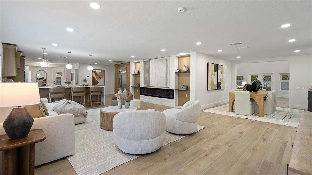An open-concept living room features a fireplace, neutral furniture, and light wood flooring — 4623 W BROWNING AVENUE, TAMPA, FL