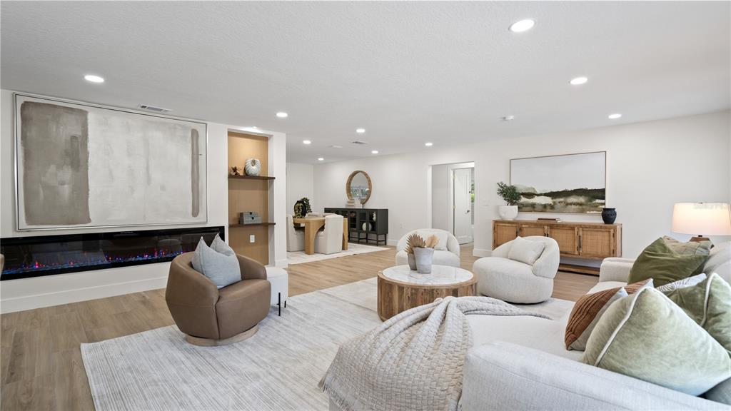 A modern living room features a linear fireplace, neutral furniture, and light wood flooring — 4623 W BROWNING AVENUE, TAMPA, FL
