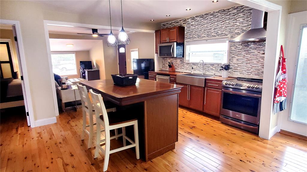 A kitchen features a wooden island, stainless steel appliances, and light wood flooring — 1722 ALBEMARLE ROAD, CLEARWATER, FL