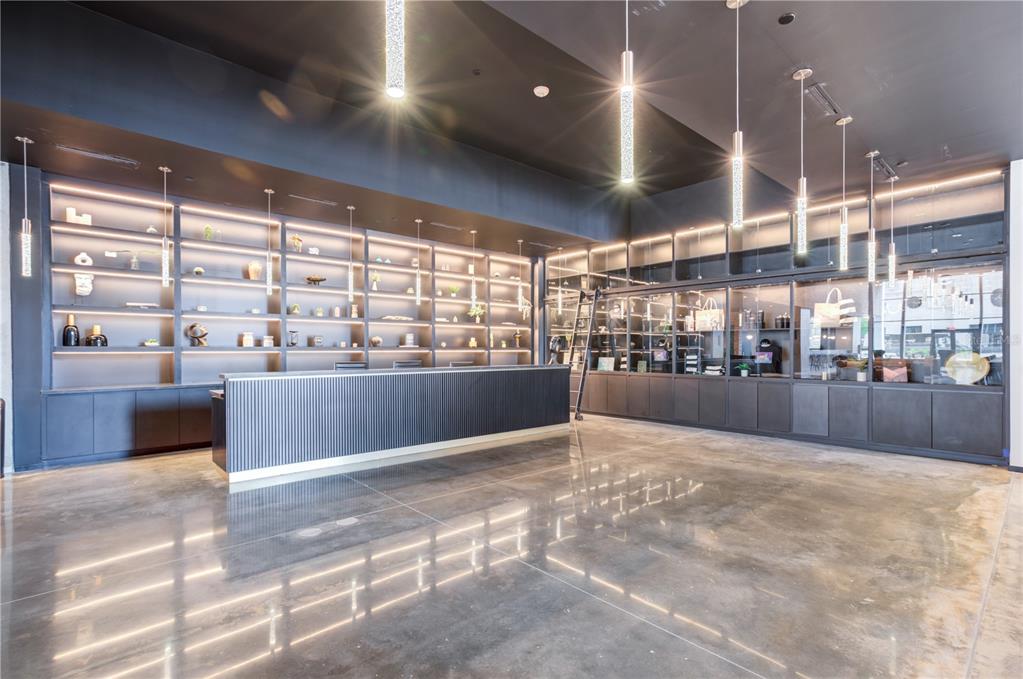 A modern commercial space features a long reception desk, illuminated shelving, and polished concrete floors — 434 N ORANGE AVENUE, ORLANDO, FL