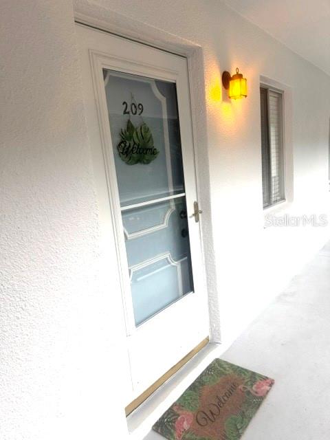 A white exterior door with a glass storm door and a welcome mat — 2060 MARILYN STREET UNIT 209, CLEARWATER, FL