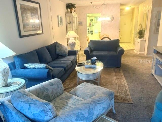 A living room features a blue sofa, a matching armchair, and a glass-topped coffee table — 2060 MARILYN STREET UNIT 209, CLEARWATER, FL