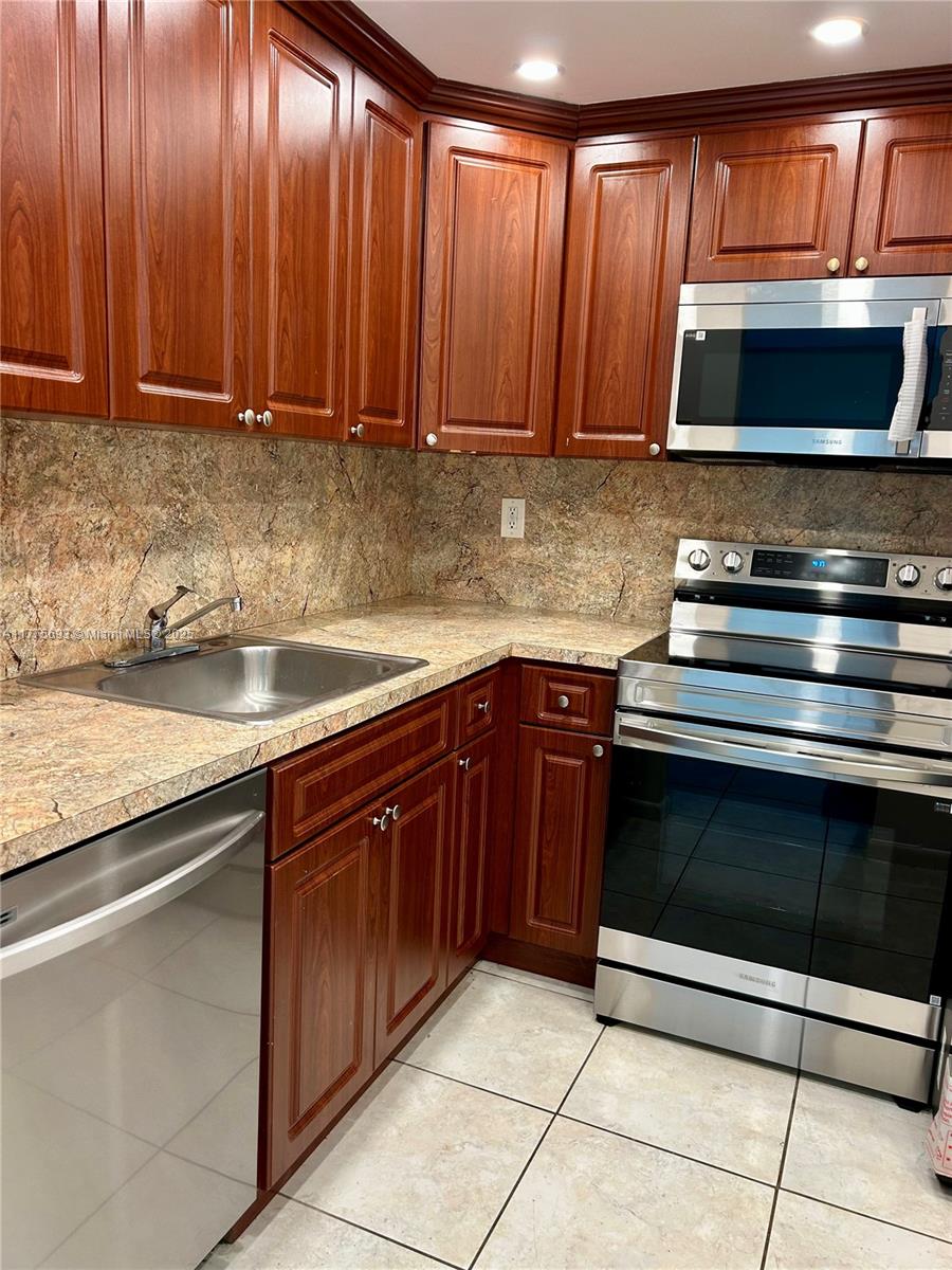 A kitchen features cherry wood cabinets, granite countertops, and stainless steel appliances — 484 NW 165th St Rd # 316, Miami FL 33169, MIAMI, FL