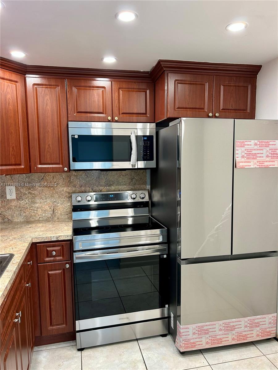 A kitchen features dark wood cabinets, stainless steel appliances, and granite countertops — 484 NW 165th St Rd # 316, Miami FL 33169, MIAMI, FL