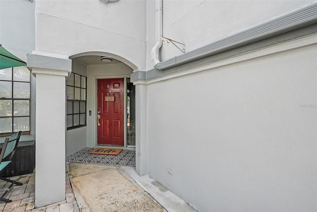 A red front door is recessed under an arched entryway with a patterned floor mat — 4107 BRENTWOOD PARK CIRCLE, TAMPA, FL