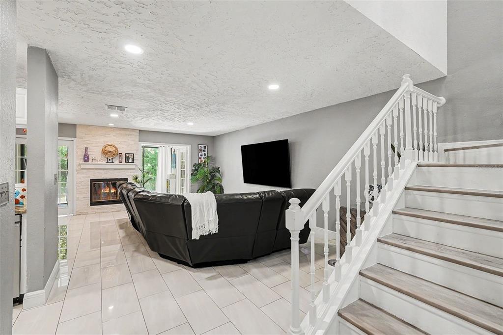 A living room features a black sectional sofa, a fireplace, and a staircase with white railings — 4107 BRENTWOOD PARK CIRCLE, TAMPA, FL