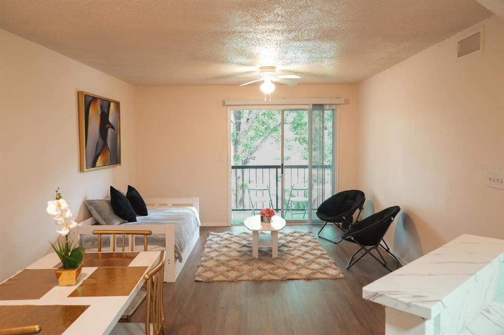 A living room with a daybed, two black chairs, a rug, and a sliding glass door — 1916 LAKE ATRIUMS CIRCLE UNIT 44, ORLANDO, FL