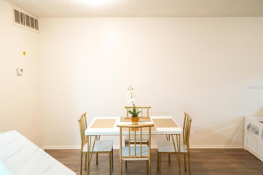 A dining area features a white table with gold chairs against a plain white wall — 1916 LAKE ATRIUMS CIRCLE UNIT 44, ORLANDO, FL