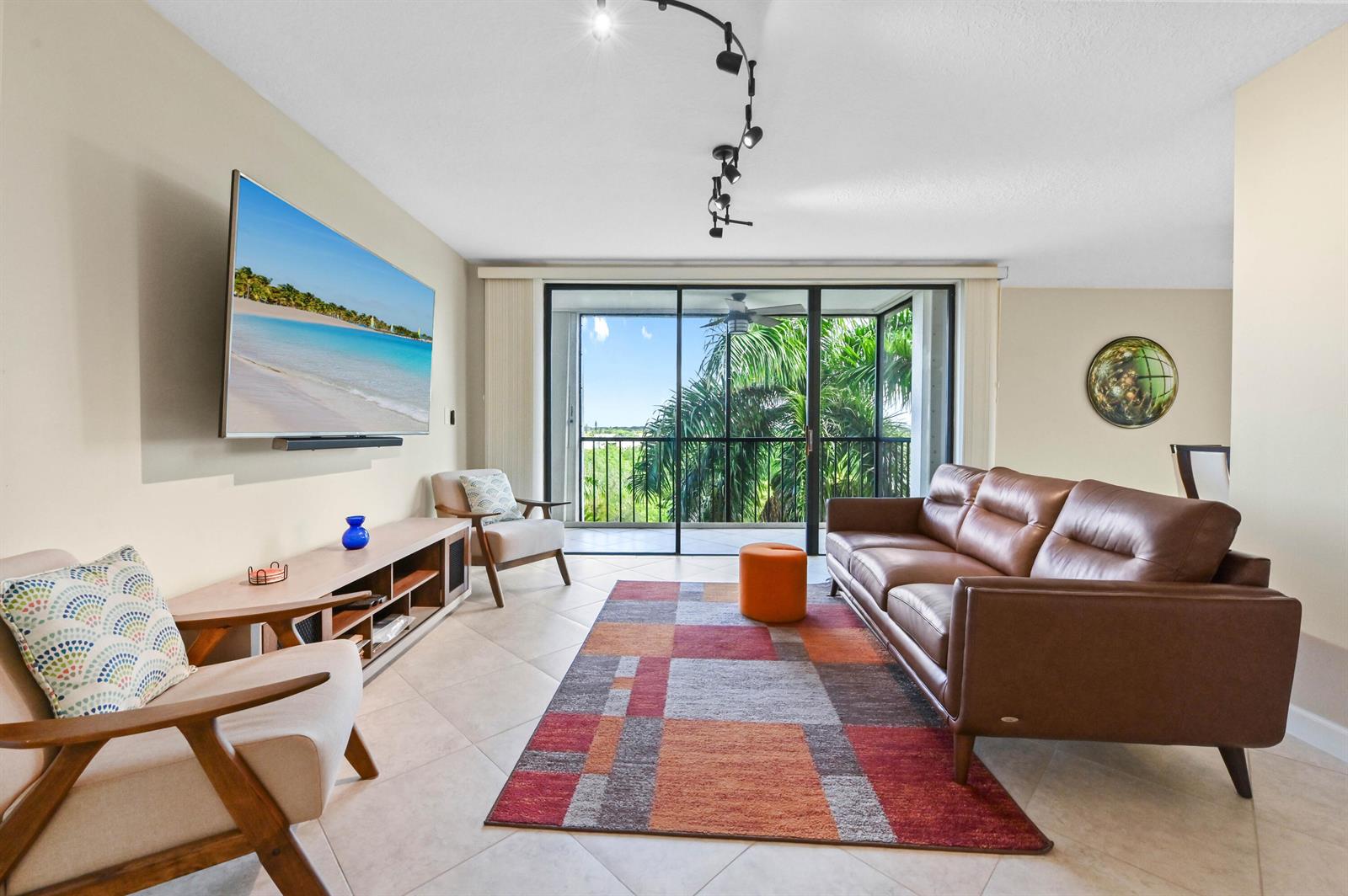 A living room features a leather sofa, two armchairs, a patterned rug, and a balcony view — 5951 Wellesley Park Drive Apt 702, Boca Raton FL 33433, BOCA RATON, FL