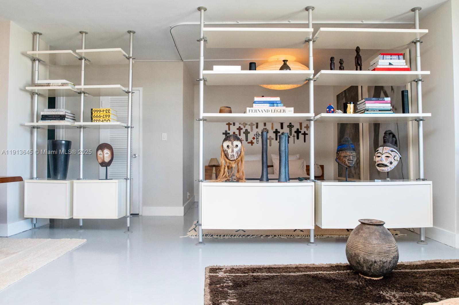 A room features white industrial-style shelving units displaying various masks, books, and decorative objects — 1000 West Ave # 1504, Miami Beach FL 33139, MIAMI BEACH, FL