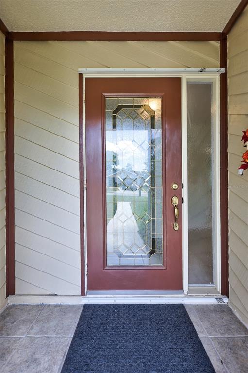 A front entryway features a red door with a glass insert and a side window — 1735 ABERDEEN COURT, PALM HARBOR, FL