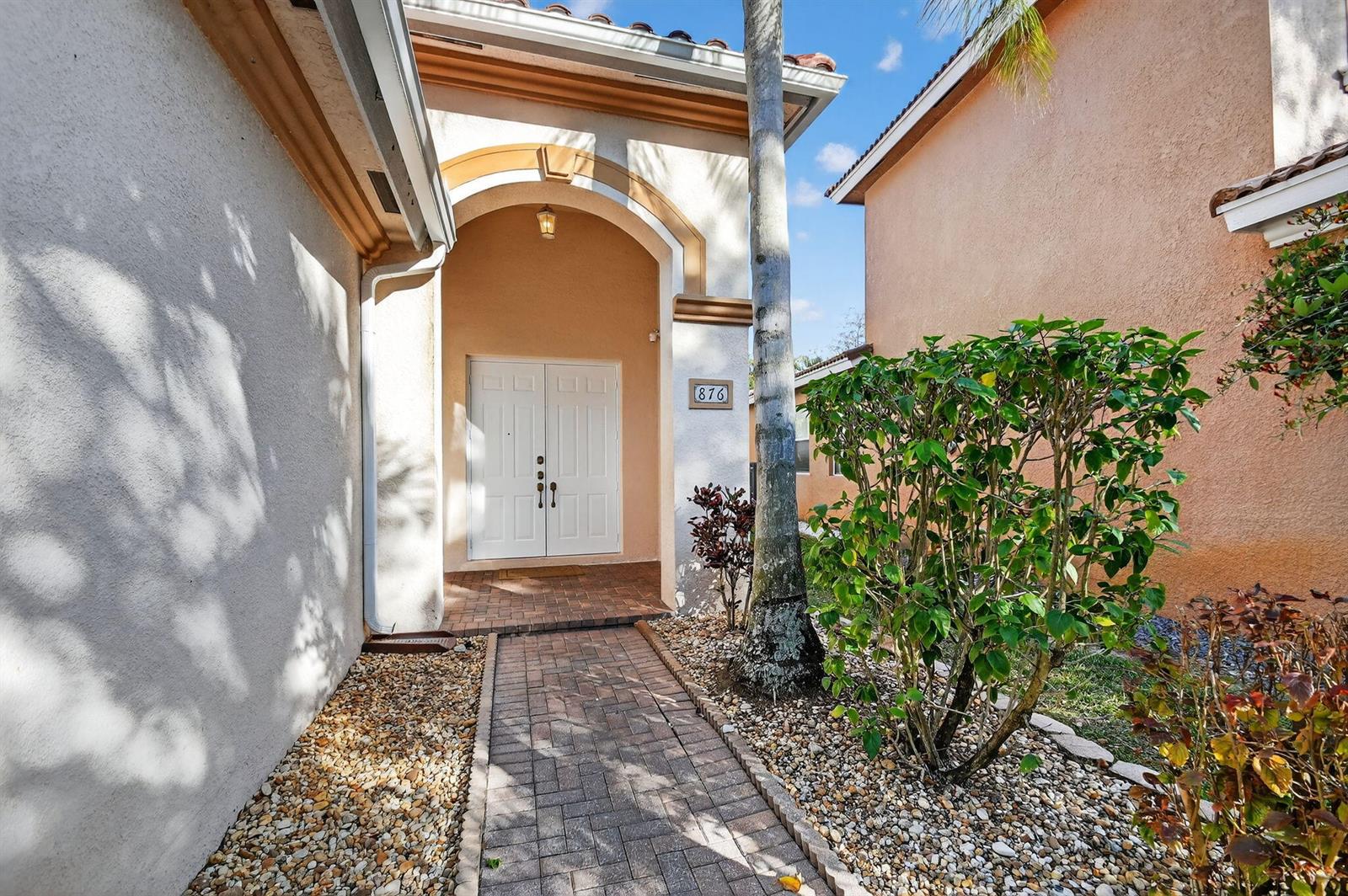 A paved walkway leads to the white double front doors of a stucco house — 876 Gazetta Way, West Palm Beach FL 33413, WEST PALM BEACH, FL