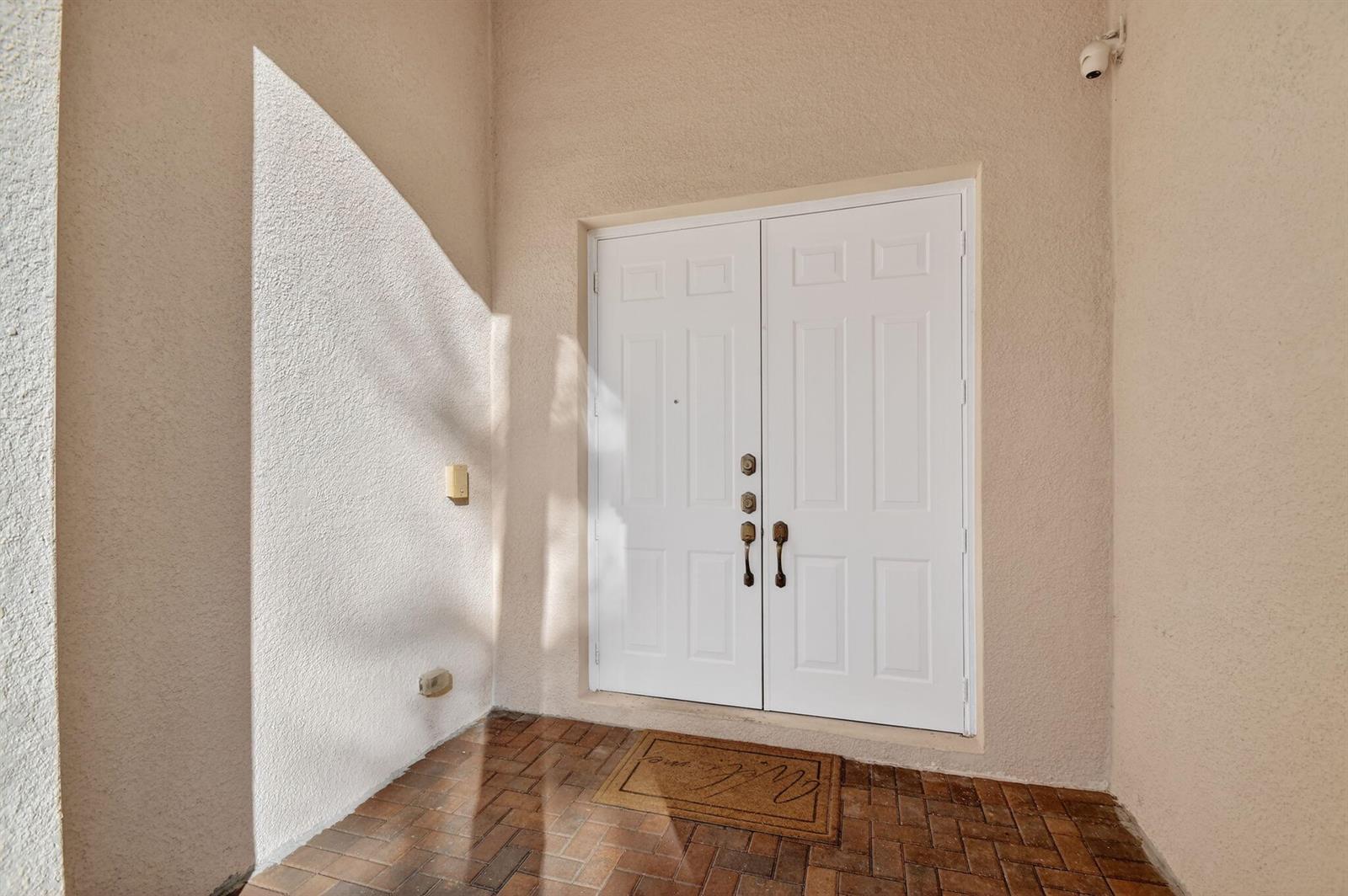 A white double front door with brass hardware sits on a brick-paved entryway porch — 876 Gazetta Way, West Palm Beach FL 33413, WEST PALM BEACH, FL