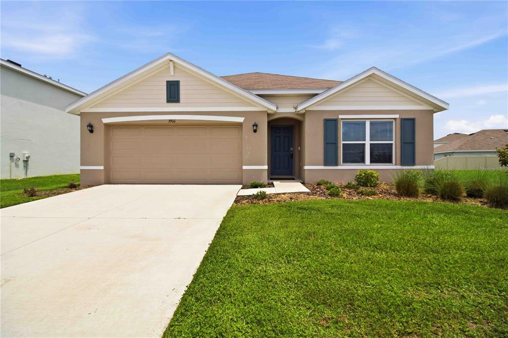 A single-story suburban house with a tan exterior, a two-car garage, and a front lawn — 3906 111TH STREET E, PALMETTO, FL