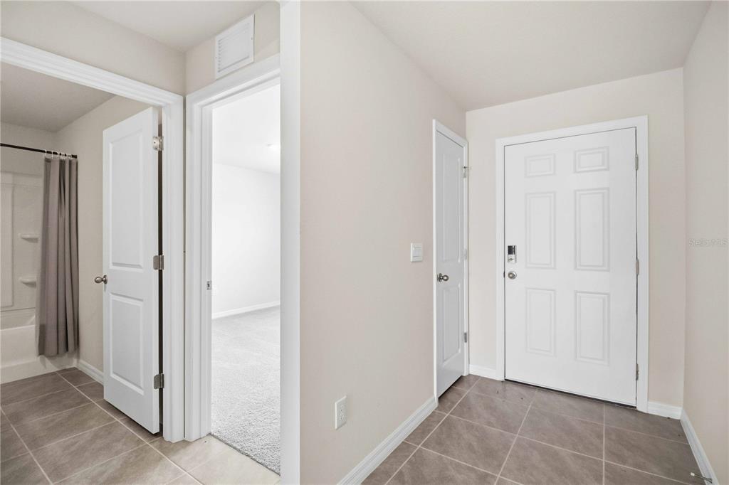 A tiled entryway features a white front door, a closet, and doorways to a bathroom and bedroom — 3906 111TH STREET E, PALMETTO, FL