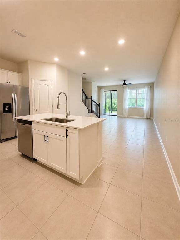 A kitchen with a white island and stainless steel appliances opens to a living area — 339 REDBUD ROAD, PALM COAST, FL