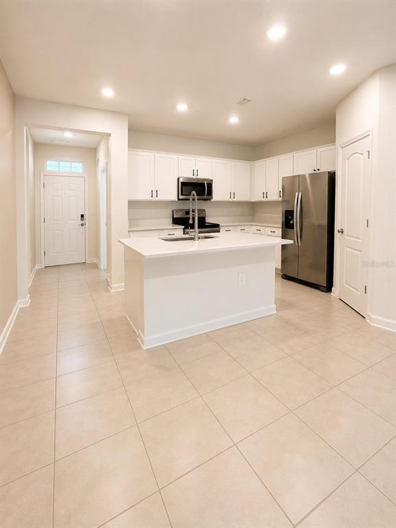 A kitchen features white cabinets, stainless steel appliances, a center island, and tile flooring — 339 REDBUD ROAD, PALM COAST, FL