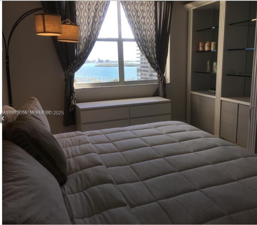 A bedroom features a bed, a low dresser, built-in shelving, and a window with water views — 11111 Biscayne Blvd # 4D, Miami FL 33181, MIAMI, FL