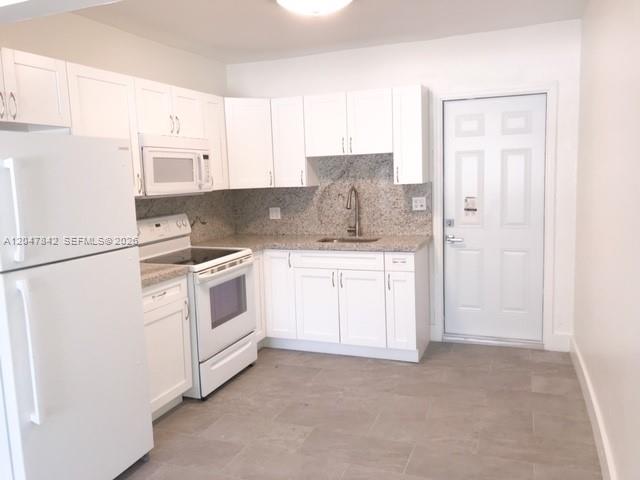 A kitchen features white cabinets, granite countertops, stainless steel appliances, and light tile flooring — 2194 NW 18th Ter # 0, Miami FL 33125, MIAMI, FL