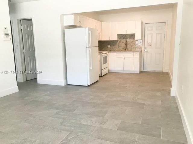 A kitchen with white cabinets and appliances features light gray tile flooring — 2194 NW 18th Ter # 0, Miami FL 33125, MIAMI, FL