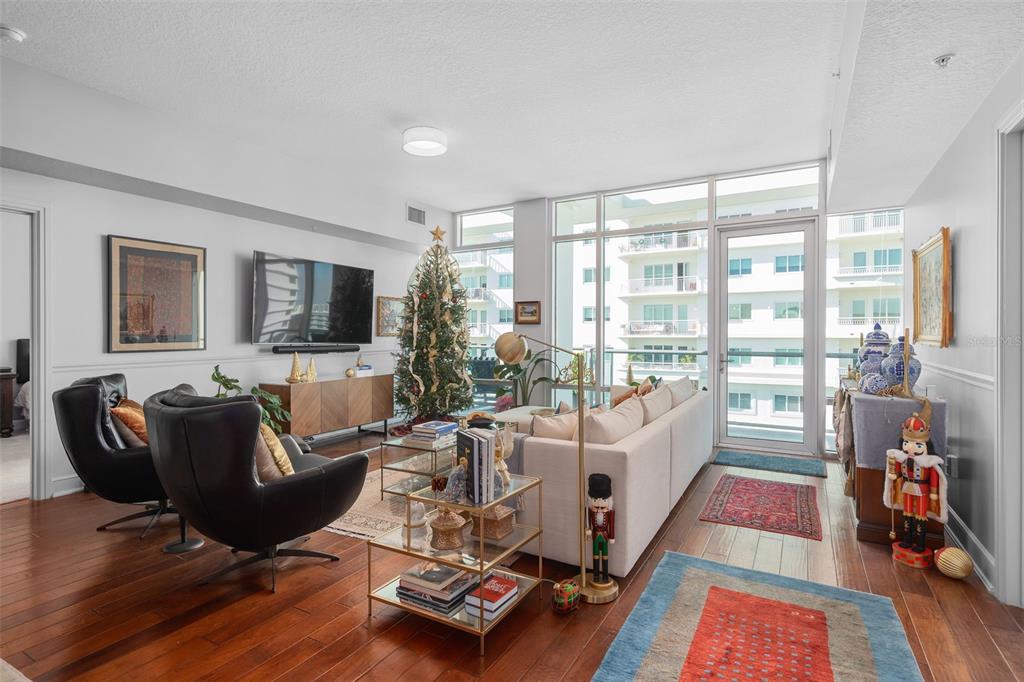 A living room features hardwood floors, a Christmas tree, a sofa, and floor-to-ceiling windows — 101 S EOLA DRIVE UNIT 1209, ORLANDO, FL