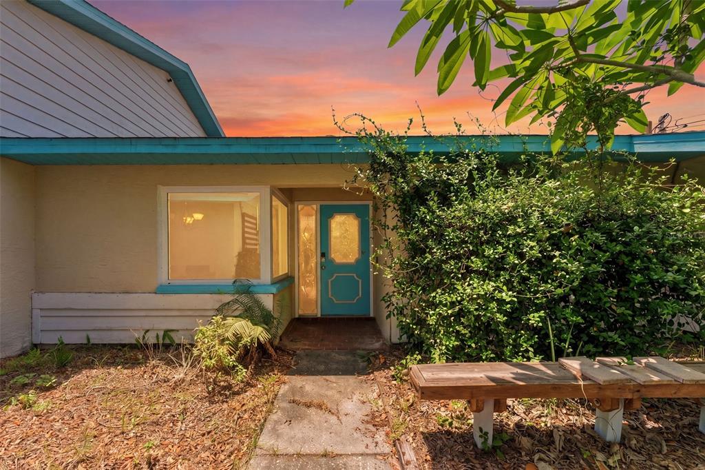 A house exterior features a turquoise front door, a large window, and a wooden bench — 670 SPARROW AVENUE, PALM HARBOR, FL