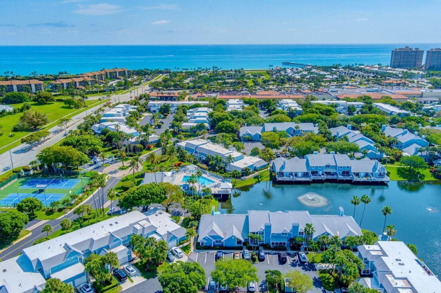 An aerial view of a coastal residential complex with a pool, tennis courts, and lake — 716 Ocean Dunes Circle, Jupiter FL 33477, JUPITER, FL