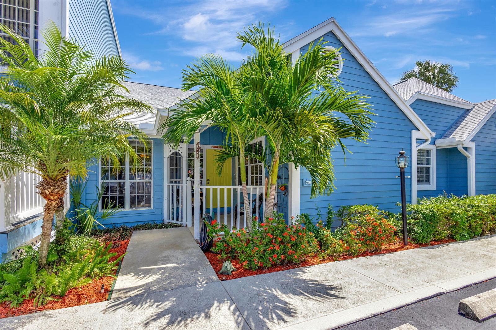 A blue house with a white porch, palm trees, and red flowers in the front yard — 716 Ocean Dunes Circle, Jupiter FL 33477, JUPITER, FL
