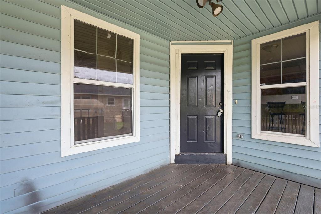 A porch with light blue siding, a dark front door, and two windows — 38407 LOWELL HARRIS WAY, DADE CITY, FL