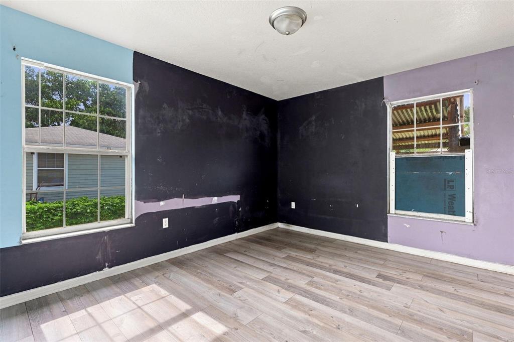 An unfinished bedroom features dark walls, light wood-look flooring, and two windows — 38407 LOWELL HARRIS WAY, DADE CITY, FL