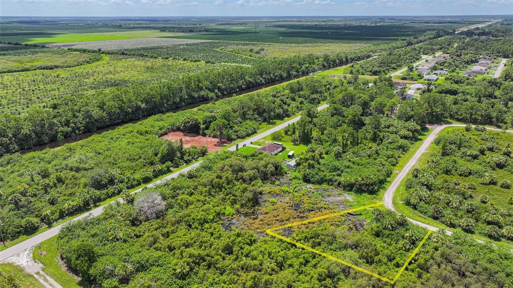 An aerial view shows a rectangular plot of land outlined in yellow near a rural road — 1245 CAVALIER CIRCLE, LEHIGH ACRES, FL
