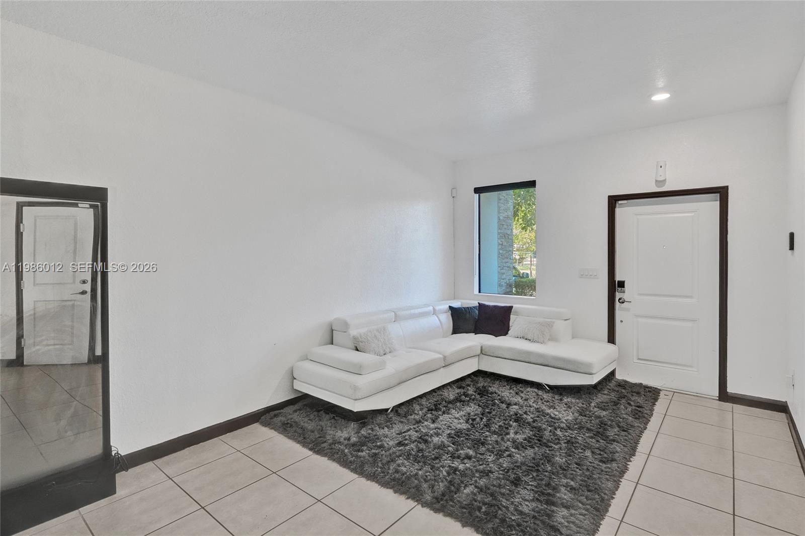 A living room features a white sectional sofa, a gray shag rug, and tile flooring — 408 NE 212th Ter, Miami FL 33179, MIAMI, FL