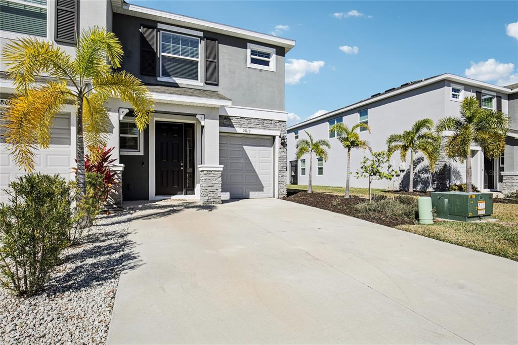 A two-story townhouse with a concrete driveway, a black front door, and palm trees — 2813 MIDNIGHT PEARL DRIVE, SARASOTA, FL