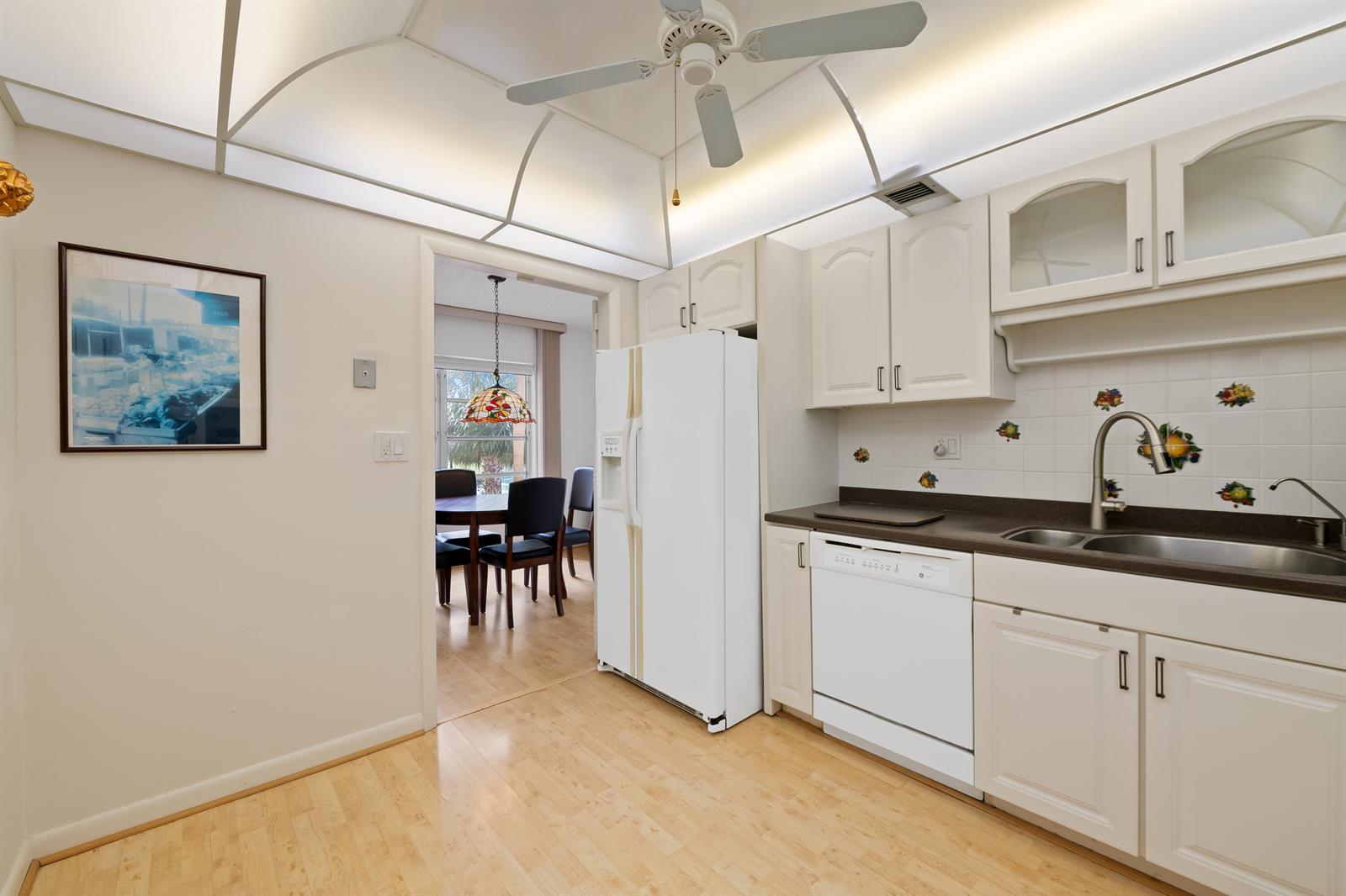A kitchen with white cabinets, a white dishwasher, and a refrigerator, featuring a ceiling fan — 10777 W Sample # 207, Coral Springs FL 33065, CORAL SPRINGS, FL