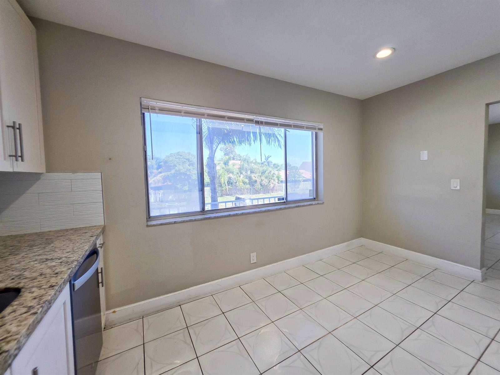 A kitchen dining area features white tile floors, beige walls, and a large window — 6289 Lear Drive # 203, Lake Worth FL 33462, LAKE WORTH, FL